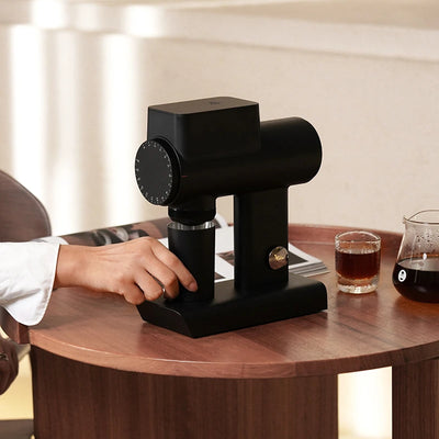 TIMEMORE Sculptor 064s grinder in use, showcasing its sleek design and functionality on a wooden table.